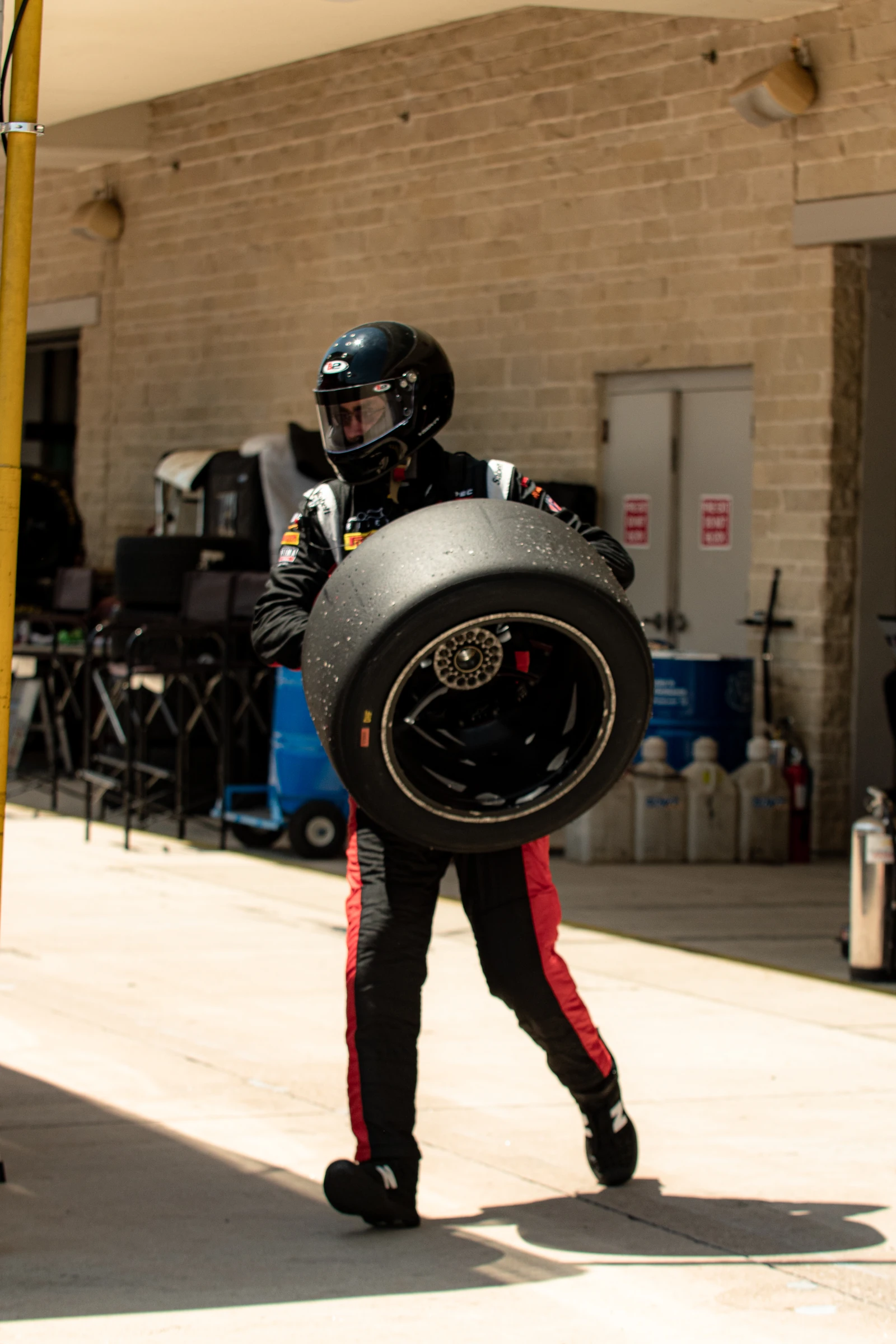 Crew member carrying a racing wheel through the paddock