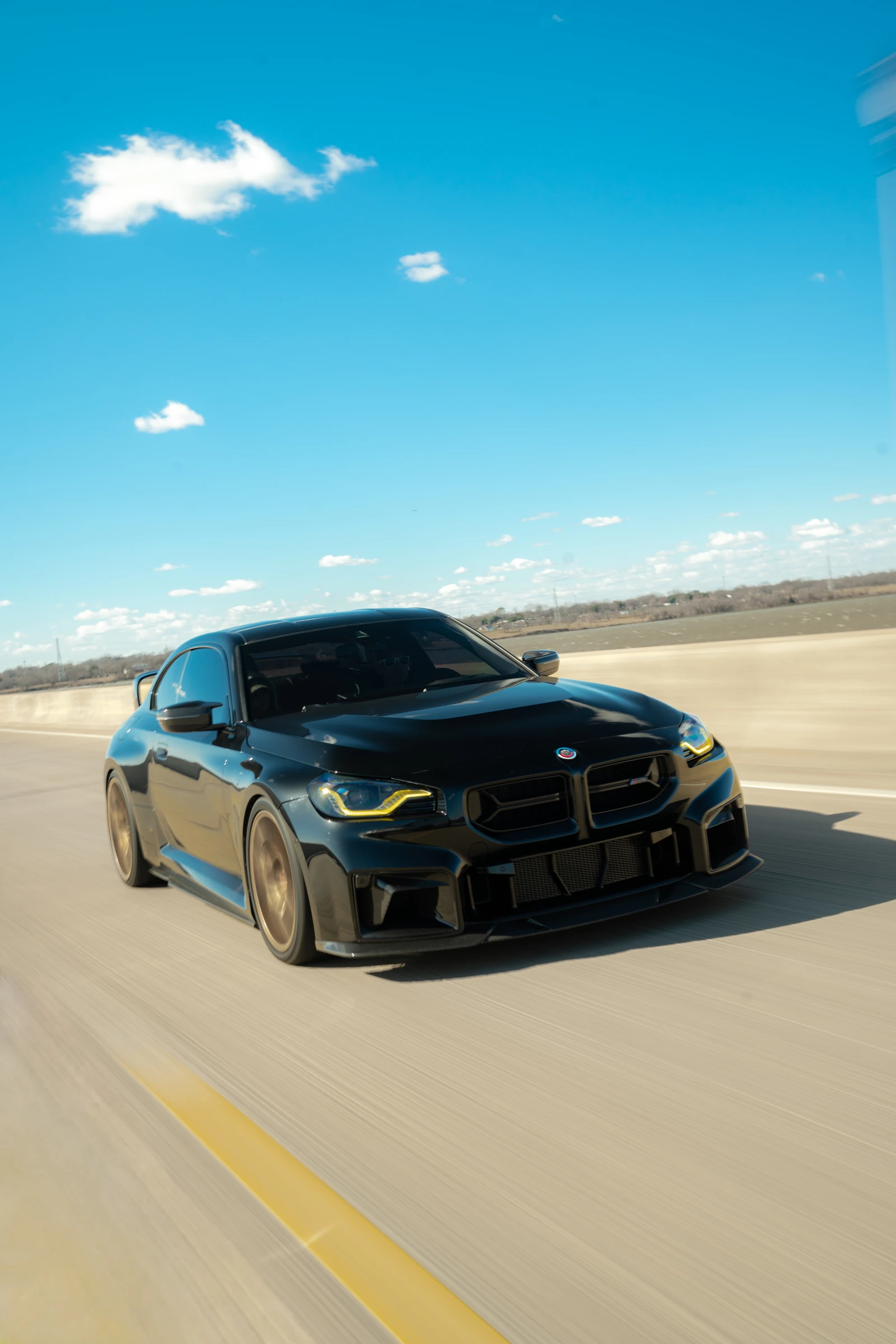 Front portrait of Erick’s black BMW M2 on the road