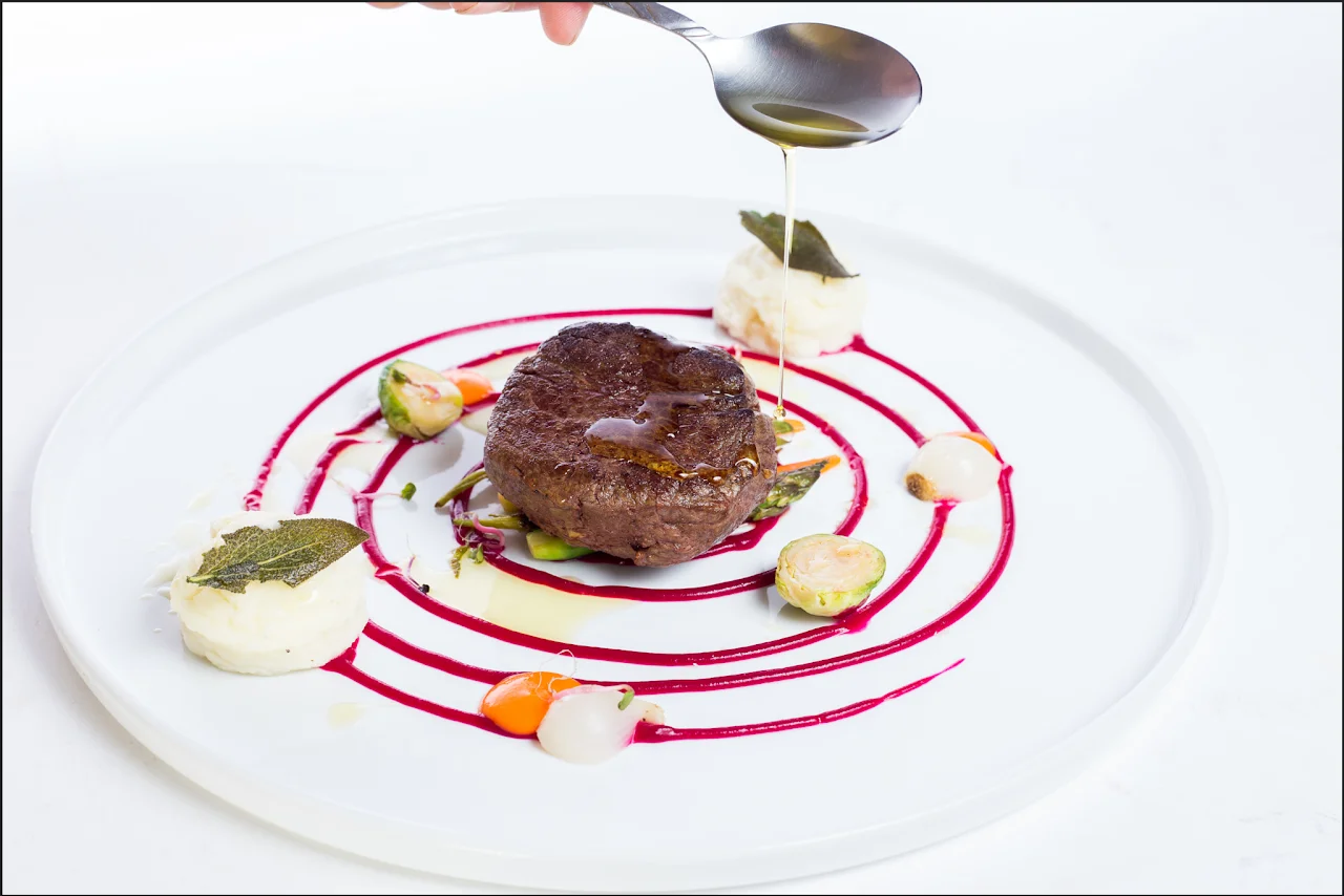 Fine dining dish with colorful sauces and a finishing touch