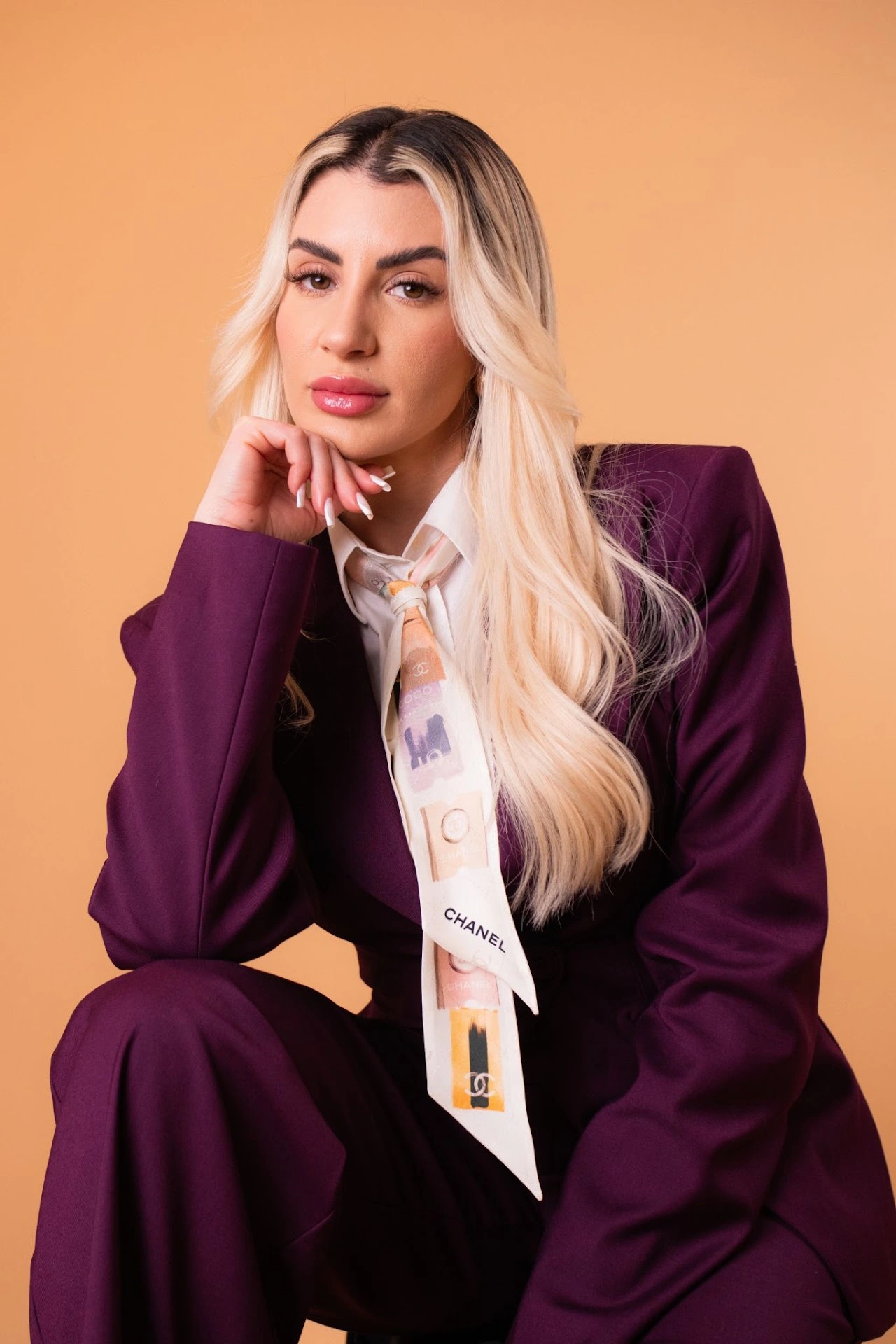 Editorial portrait in a plum suit against a warm studio backdrop